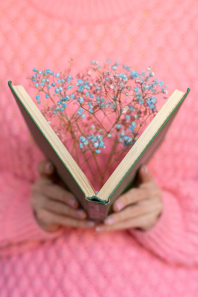 Kobieta trzyma otwartą książkę, a w niej kwiaty. Poezja w biznesowych tekstach